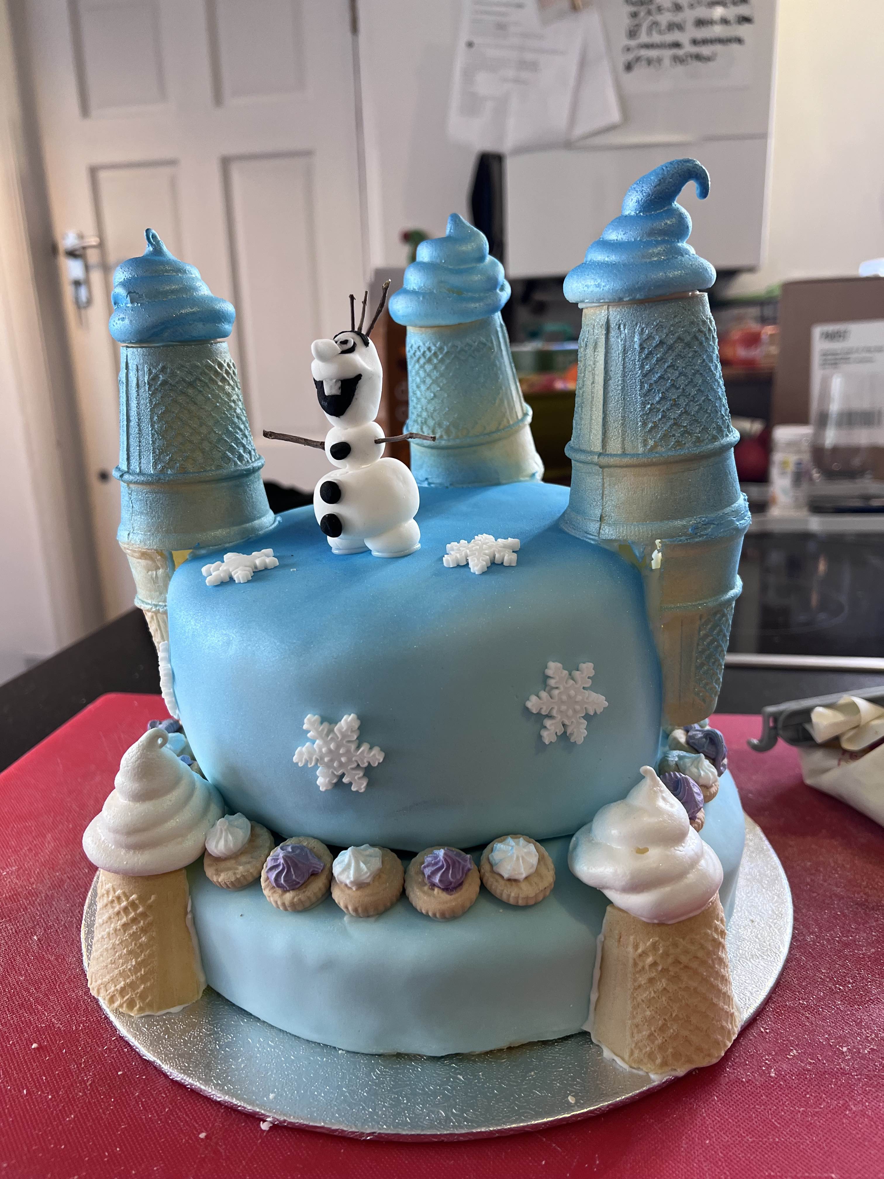 Blue castle cake with ice cream cone and meringue turretts and Olaf the snowman