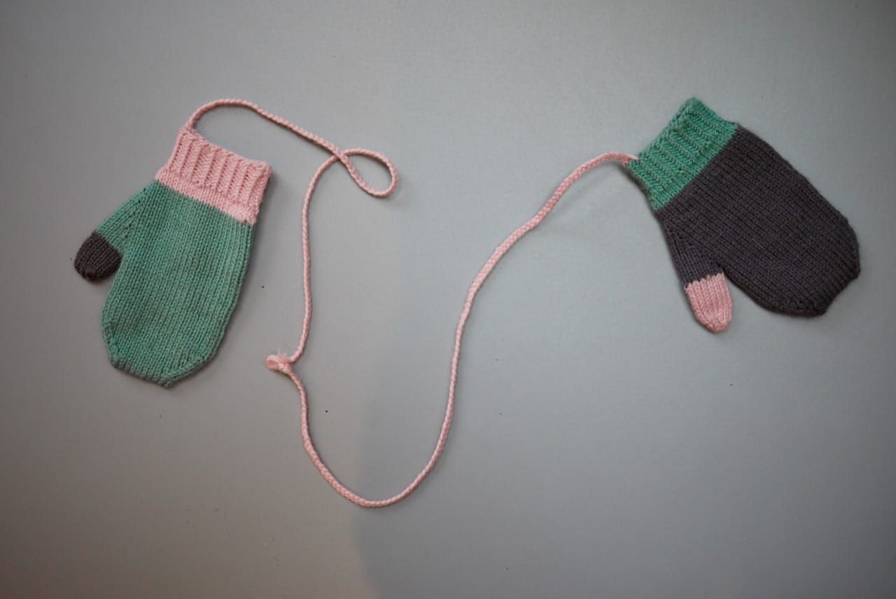 Pink, grey and green mittens attached with string